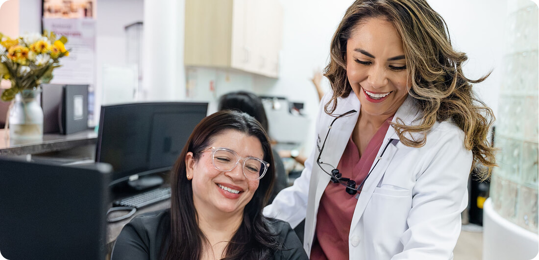 Dentist and her assistant smiling